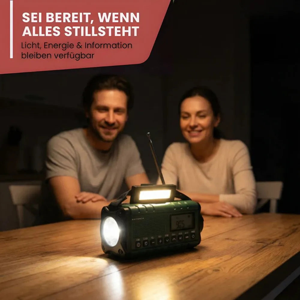 Grünes Kurbelradio mit Leselicht auf einem Holztisch, dahinter ein Paar am Abend