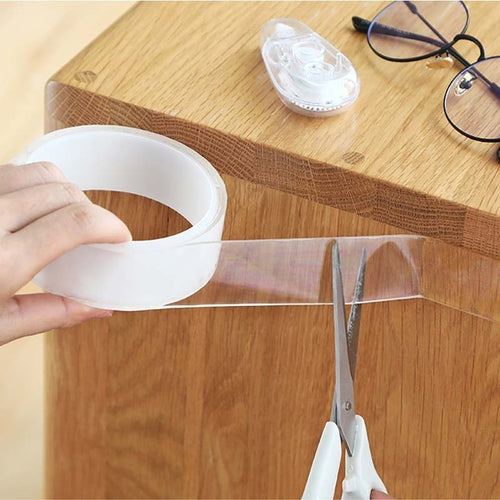 Transparentes Montageband wird an einer Holzkante mit der Schere abgeschnitten